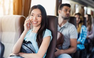 A happy female passenger talking on her phone while traveling